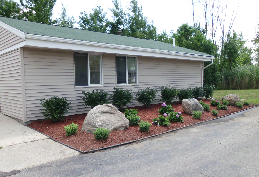 the front of our house with a flower bed and rocks